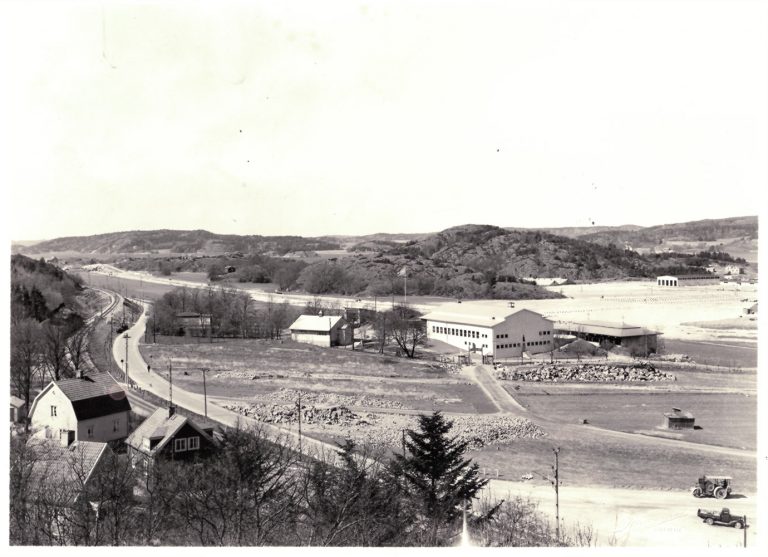 Vy med hus, väg, fält och större byggnad som är folkets park Uddevalla.