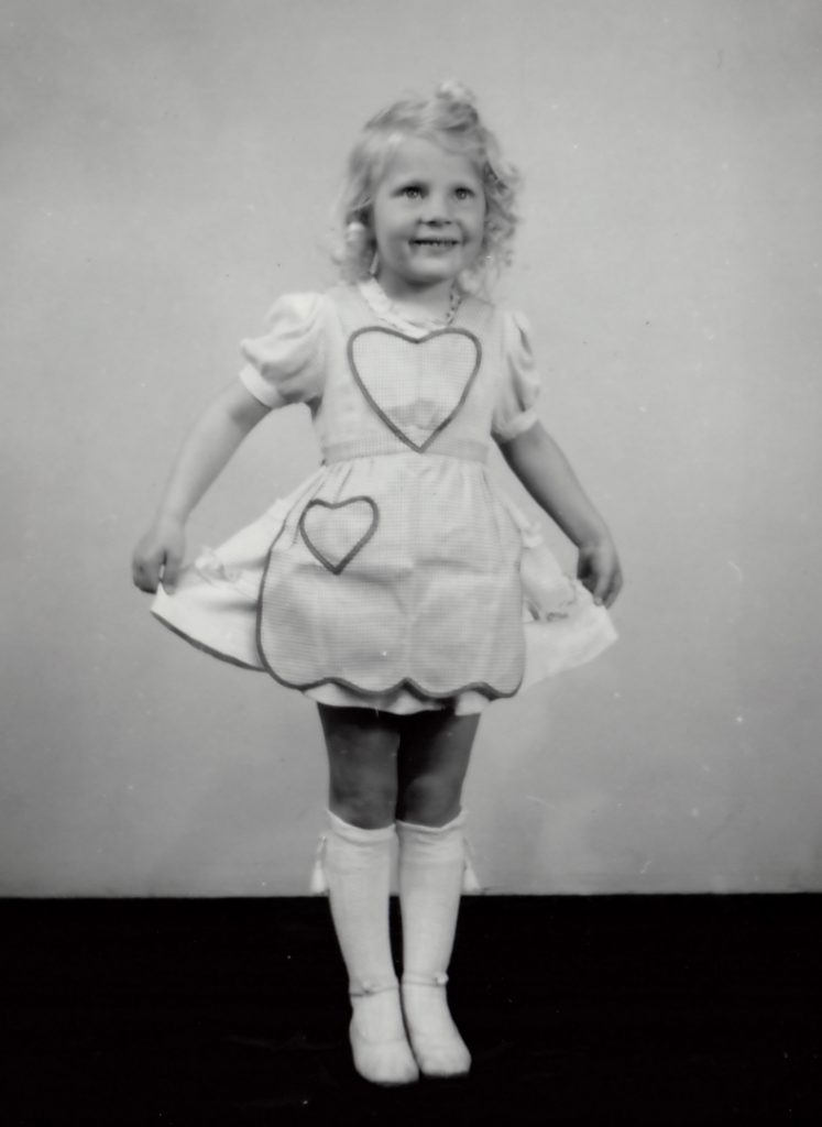 Yngre tjej ca 6 år visar upp sin klänning med två hjärtan på.