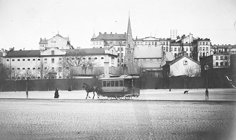 Centralfängelset till vänster i bild. Mitt i bilden en kyrka och i förgrunden en hästdragen spårvagn.